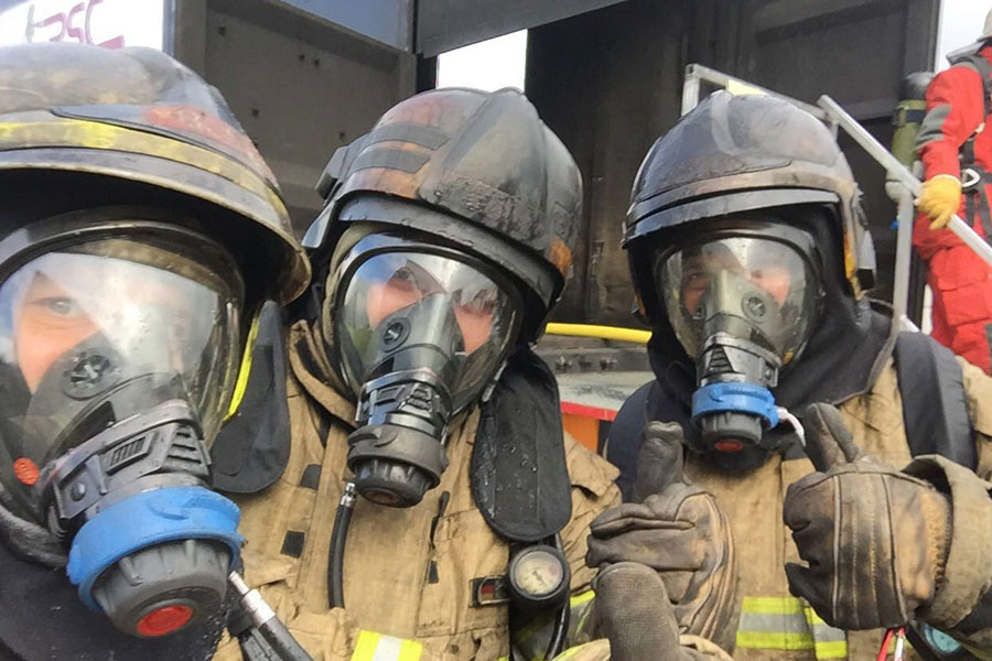 Drei Feuerwehrleute mit verschmutzer Einsatzkleidung